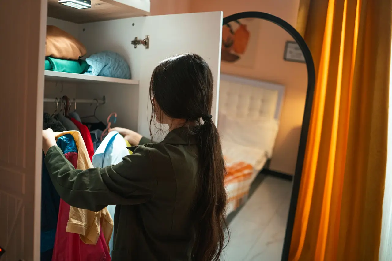 A professional organizer arranging neatly folded clothes and labeled bins on tidy closet shelves