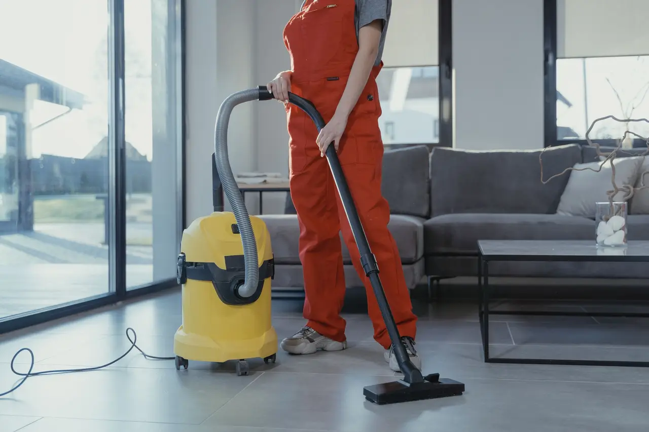 A house cleaner in uniform wiping down a kitchen counter in a bright, tidy home