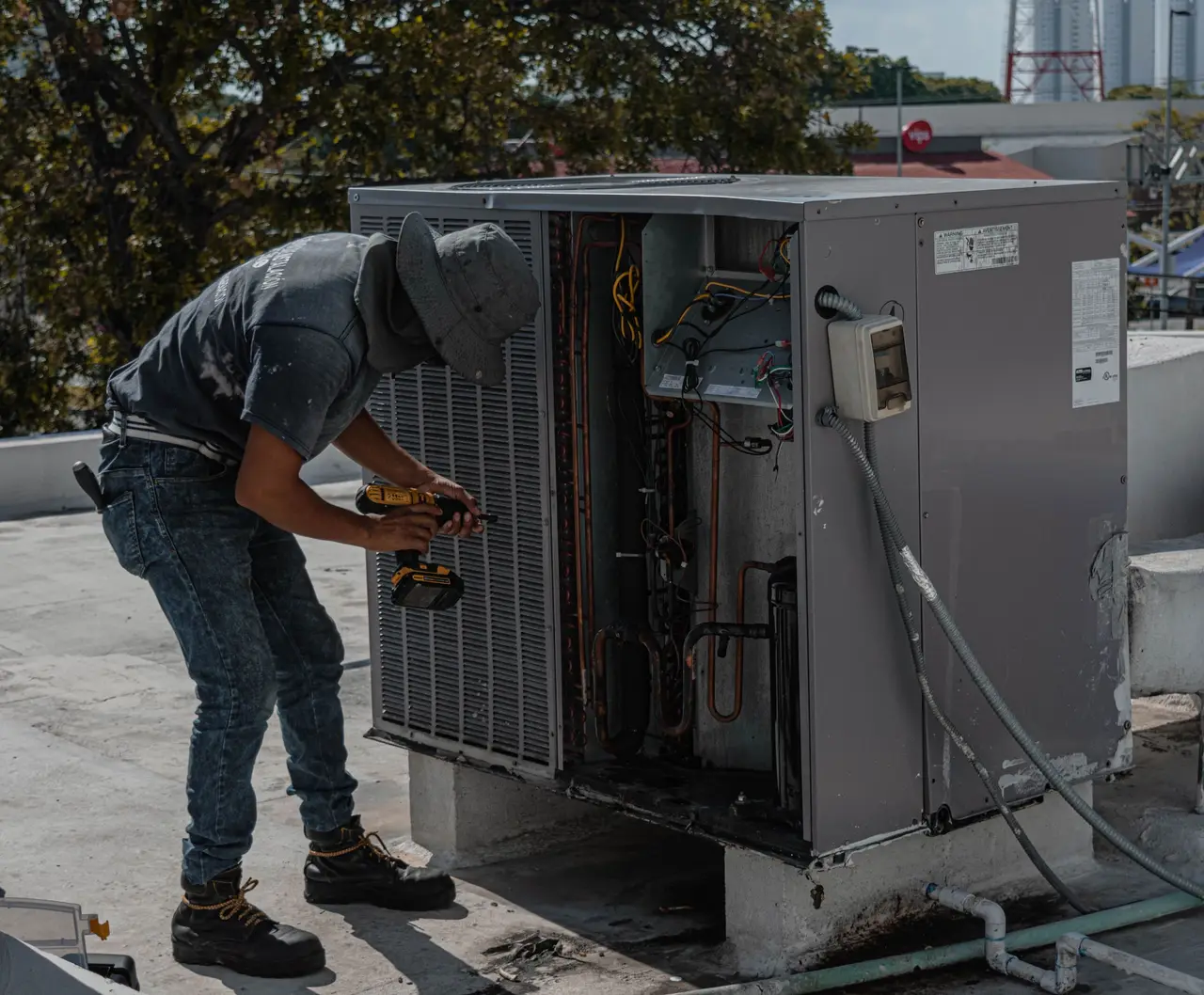 Un técnico de HVAC revisando los manómetros de refrigerante en una unidad condensadora exterior