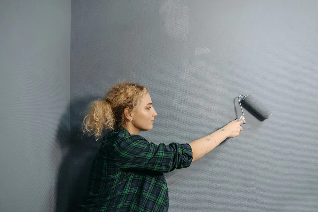 Un pintor profesional perfilando el borde de una pared con una brocha en un cuarto recién pintado